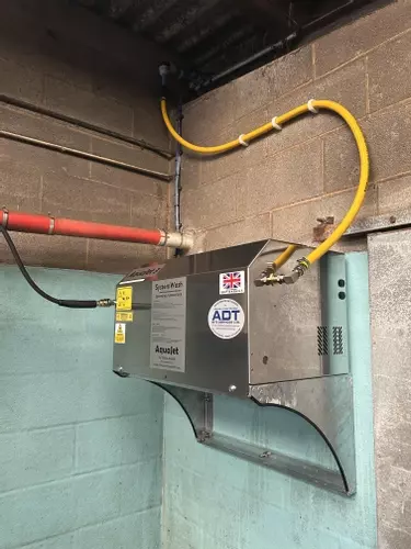 Stainless steel AquaJet 3 wall-mounted pressure washer installed at a dairy farm in Atherstone, raised for safety and protection.